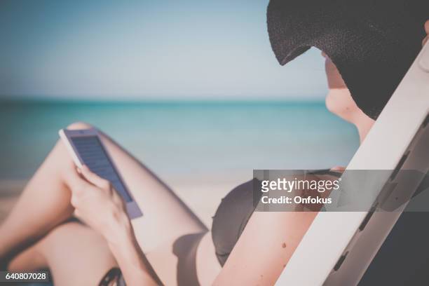 woman relaxing at beach on chair with electronic book reader - cuba beach stock pictures, royalty-free photos & images