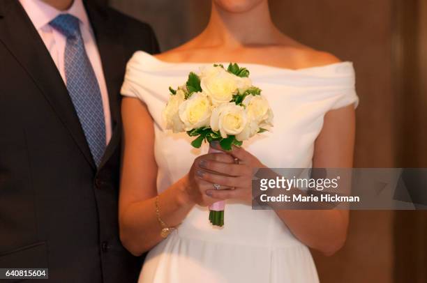 cropped wedding photo of a groom in a dark suit and blue tie and a bride holding bouquet of white flowers - white suit and tie stock pictures, royalty-free photos & images