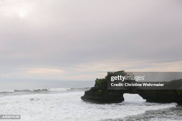 a temple built on the rocks on the coastline of bali at tanah lot. - christine wehrmeier stock pictures, royalty-free photos & images