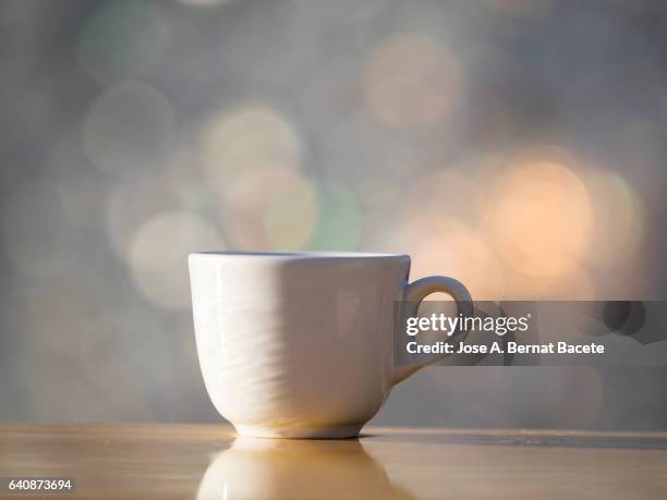 cup of coffee espresso in a cup of white porcelain, on a table of wood illuminated by the light of the sun - japanese tea cup stock pictures, royalty-free photos & images