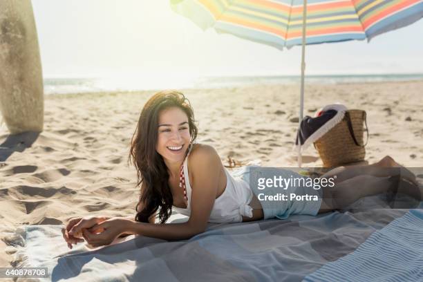 glückliche frau liegend auf decke am strand - strandschirm stock-fotos und bilder