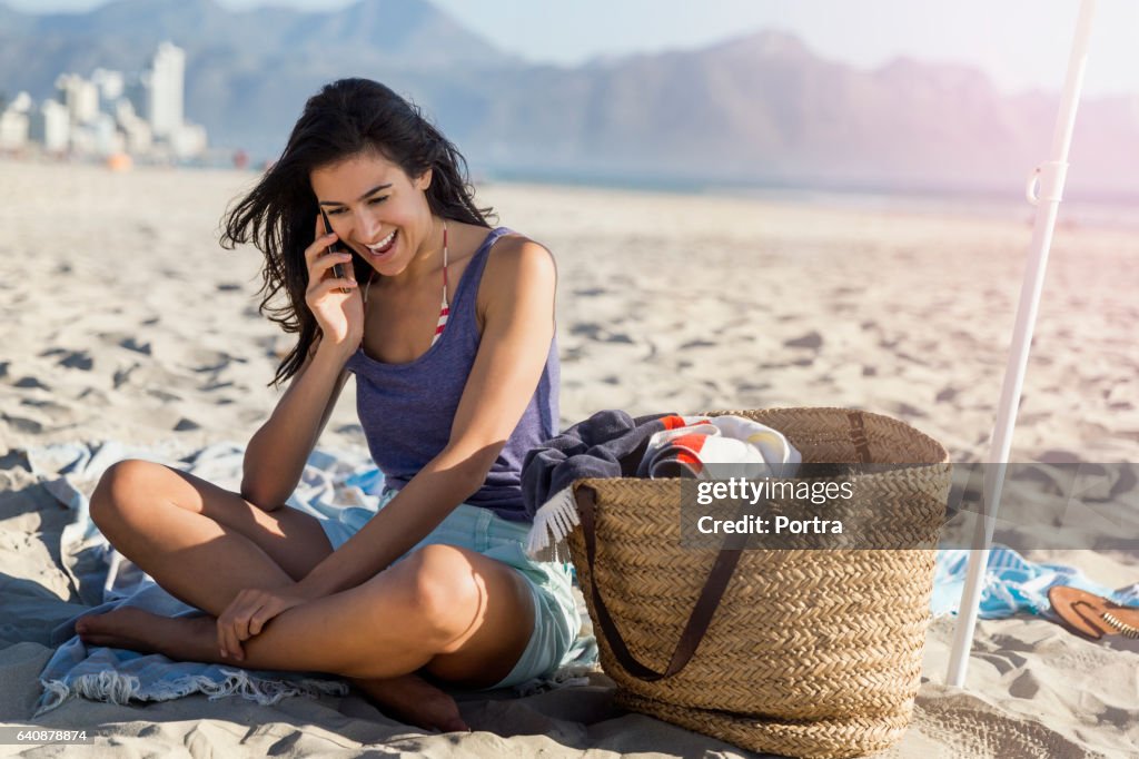 Glad kvinna med smart telefon vid stranden