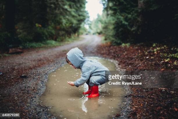 kinder spielen im regen pfütze - puddles stock-fotos und bilder