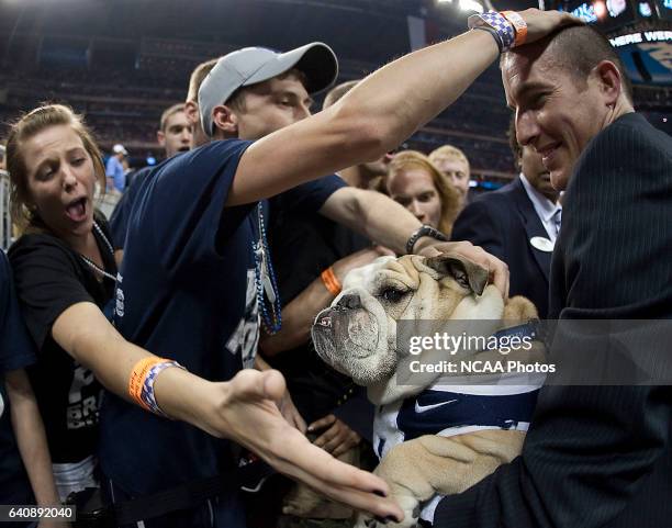 Butler fans pet Butler's Bulldog mascot, Blue II as he is carried off the court by Butler's, Mike Kaltenmark, Director of Web Marketing, right, after...