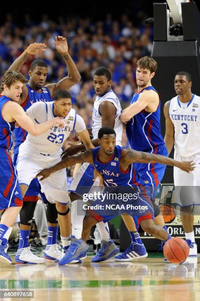 Guard Elijah Johnson from the University of Kansas tries to grab a loose ball in front of forward Anthony Davis from the University of Kentucky...