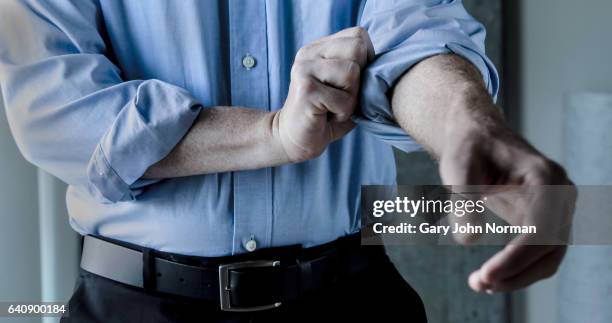 businessman rolling up shirt sleeve. - sleeve roll stock pictures, royalty-free photos & images