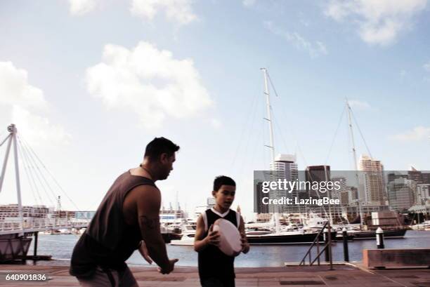 pazifikinsel mann und der junge spielt rugby gegen eine stadtansicht hafen in bewegungsunschärfe - neuseeländisches maori rugbyteam stock-fotos und bilder