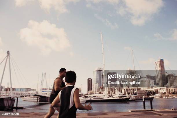 pacific island man and boy gioca a rugby contro un cityscape harbour - viaduct harbour foto e immagini stock