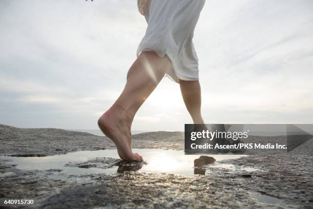 woman leaps across rock slab pool, above sea - barefoot women - fotografias e filmes do acervo