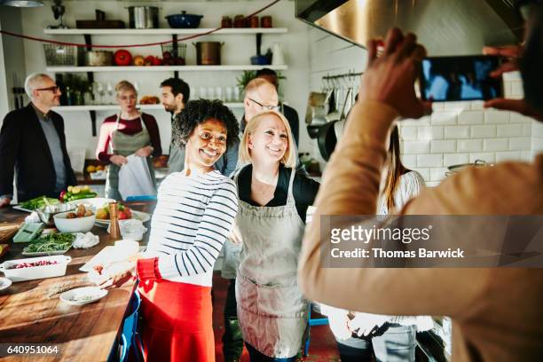 man taking a picture of smiling friends with smartphone during cooking class - christmas friends bildbanksfoton och bilder