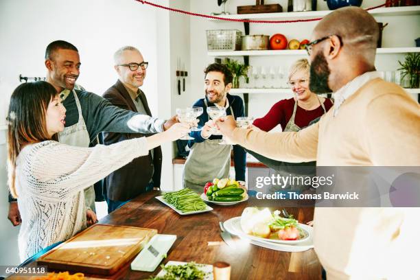 smiling group of friends toasting with champagne while preparing holiday meal - honour board stock pictures, royalty-free photos & images
