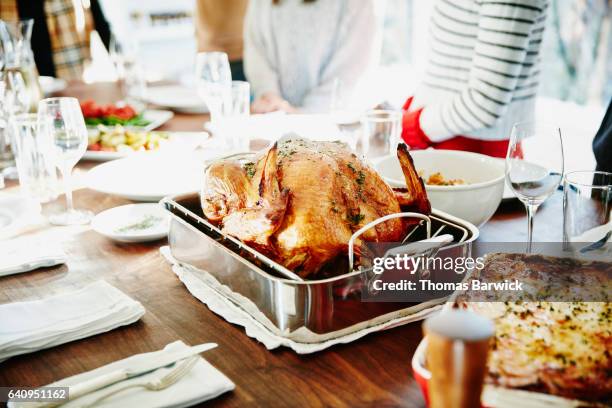 turkey in roasting pan on table for holiday meal - christmas table turkey stock pictures, royalty-free photos & images