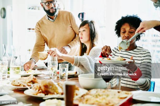 friends serving each other during holiday meal together - thanksgiving plate stock pictures, royalty-free photos & images