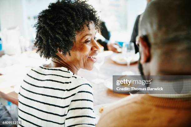 smiling woman in discussion with friend during holiday meal - 50s diner stock pictures, royalty-free photos & images