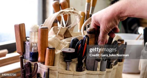 man selecting a hand tool from a bag on workbench - work tool stock pictures, royalty-free photos & images