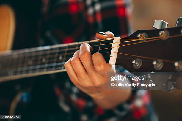 cropped image of young woman playing guitar at home - acoustic guitar foto e immagini stock