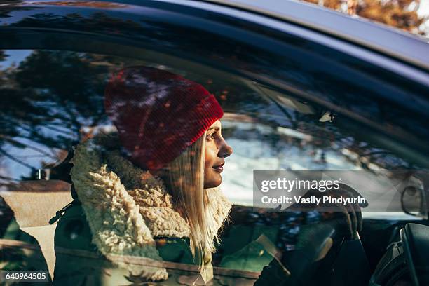 woman in warm clothing driving car - winter car foto e immagini stock