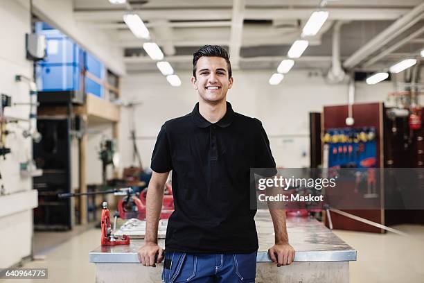 portrait of happy male auto mechanic student standing in workshop - blue collar portrait stock-fotos und bilder