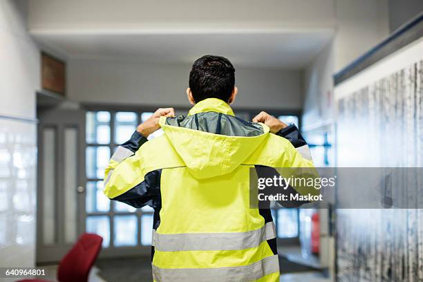 rear view of auto mechanic student wearing reflective jacket in workshop - high vis jacket man stock pictures, royalty-free photos & images
