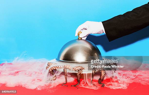 cropped image of waiter lifting domed tray against blue background - plateau stockfoto's en -beelden