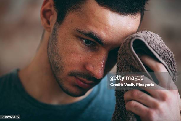 sporty man wiping sweat on forehead at gym - sudor fotografías e imágenes de stock