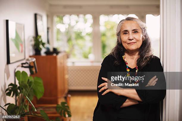 portrait of confident senior woman standing arms crossed at home - at home portrait stockfoto's en -beelden