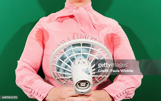 midsection of businesswoman with sweaty armpits holding fan against green background - ventilator stock-fotos und bilder