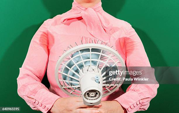 midsection of businesswoman with sweaty armpits holding fan against green background - ventilateur électrique photos et images de collection