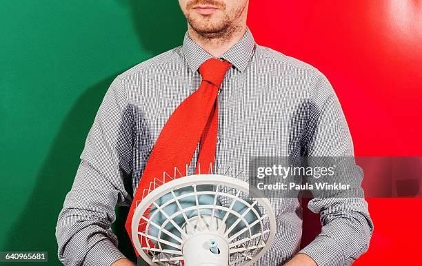 midsection of businessman with sweaty armpits holding fan against colored background - sweaty arm stock pictures, royalty-free photos & images