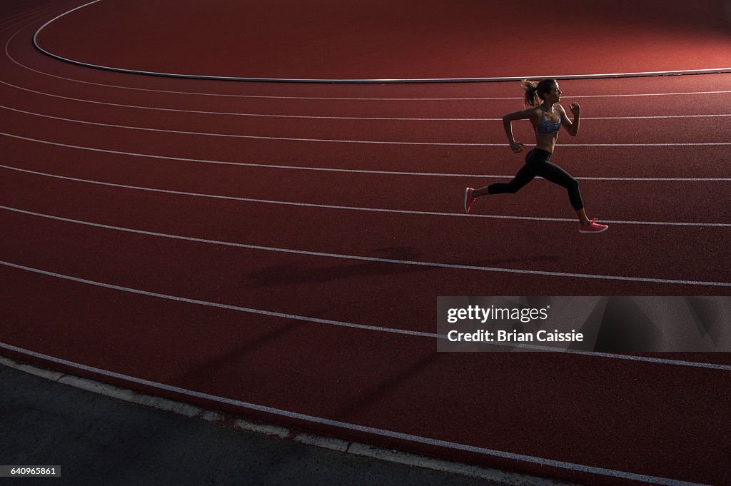 High angle view of young female athlete running on race track