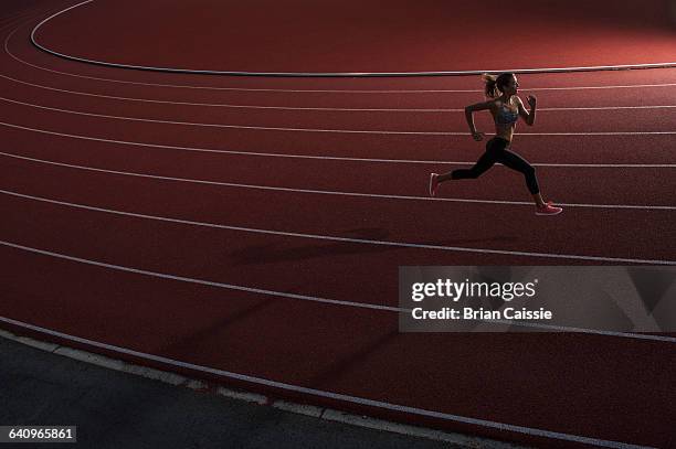 high angle view of young female athlete running on race track - leichtathlet stock-fotos und bilder