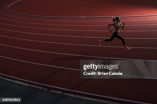 High angle view of young female athlete running on race track High angle view of young female athlete running on race track