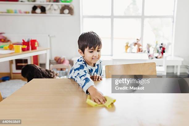 boy cleaning dining table at day care center - tidy room stock pictures, royalty-free photos & images