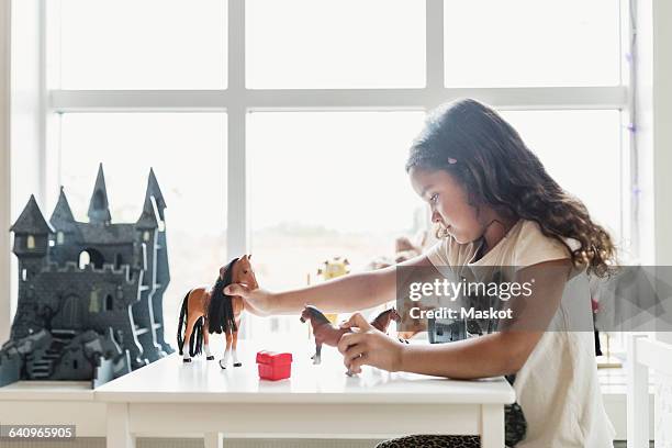 side view of girl playing with toy horses at table - horses playing stock pictures, royalty-free photos & images