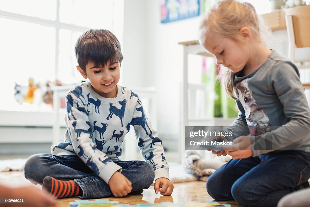 Happy children playing with jigsaw pieces at preschool