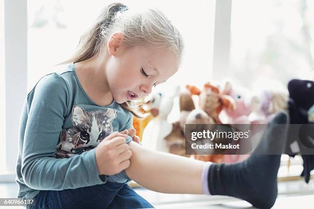 little girl looking at injured knee in classroom - injured leg stock pictures, royalty-free photos & images