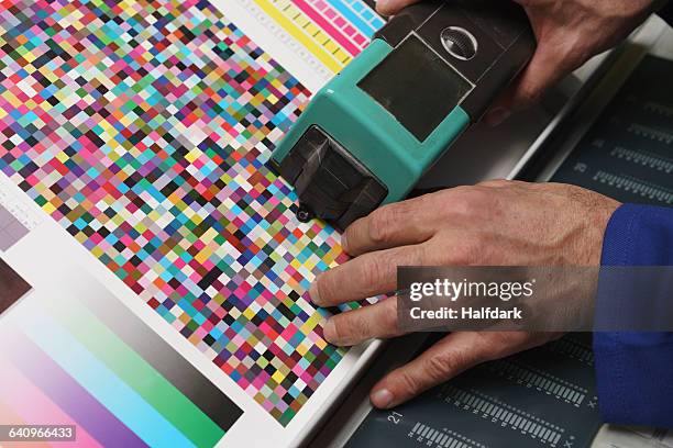 cropped image of hand holding scanner and checking quality of printed paper - drukkerij stockfoto's en -beelden