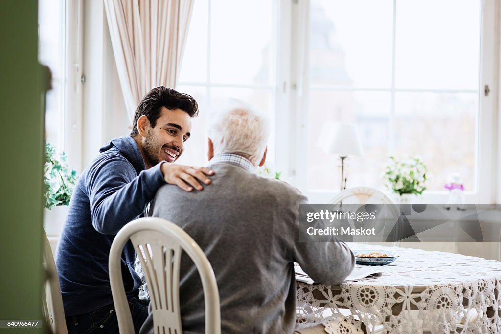 Happy caretaker communicating to senior man in nursing home