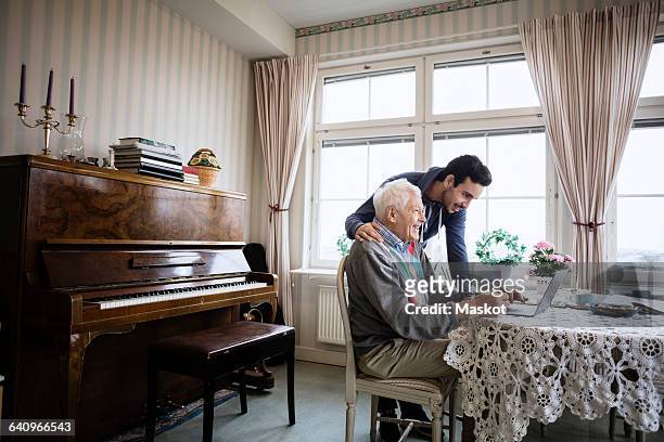 happy man using laptop with caretaker in nursing home - volunteer home care stock pictures, royalty-free photos & images