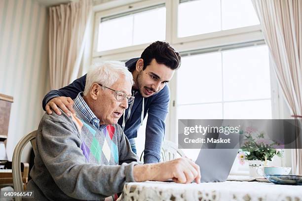 caretaker and senior man using laptop in nursing home - arab old man fotografías e imágenes de stock