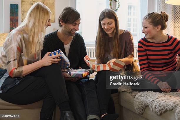 happy family looking at daughter opening birthday present in living room - birthday girl stock pictures, royalty-free photos & images