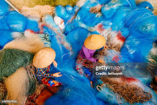 woman mending the mesh of fishing net - asian style conical hat stock pictures, royalty-free photos & images