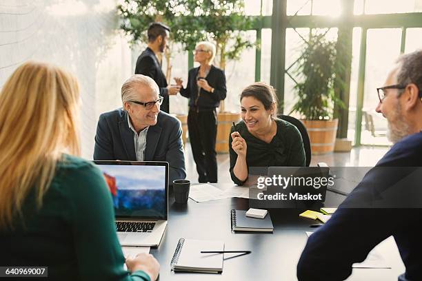 smiling businesswoman discussing with colleagues in creative office - försäljningsyrke bildbanksfoton och bilder
