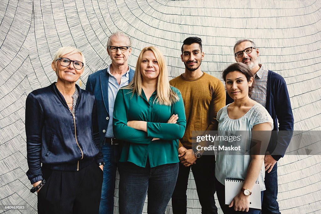Portrait of confident multi-ethnic business people standing against wall in office