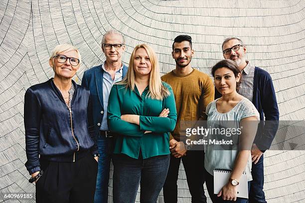 portrait of confident multi-ethnic business people standing against wall in office - medium group of people stock pictures, royalty-free photos & images