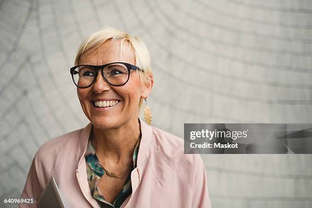 happy businesswoman wearing eyeglasses against wall - short hair women stock-fotos und bilder
