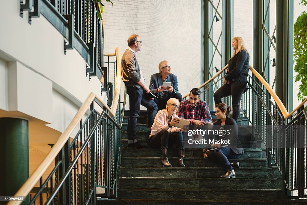 Multi-ethnic business people discussing on staircase of creative office