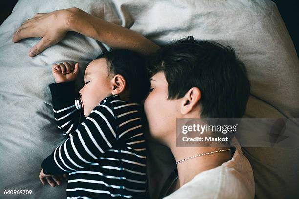 high angle view of mother and toddler sleeping on bed at home - lesbian bed stock pictures, royalty-free photos & images