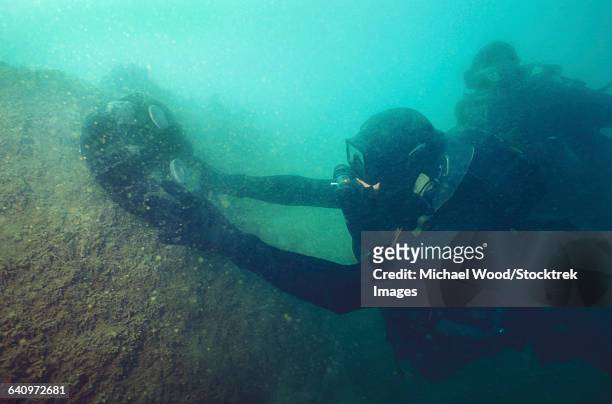 u.s. navy seal combat swimmers place a mk-1 limpet mine onto a target. - undersea mines stock pictures, royalty-free photos & images