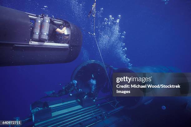 seal delivery vehicle hovers in mid-water on tether to the dry deck shelter. - submarine cable stock pictures, royalty-free photos & images